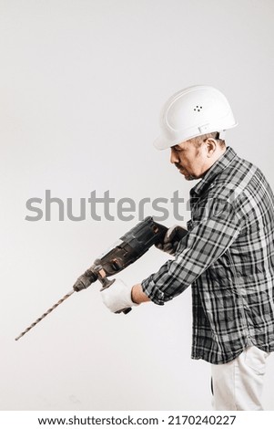 Male builder in a hard hat with a puncher on a white background