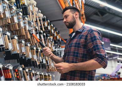 male builder in a hardware store chooses a hammer