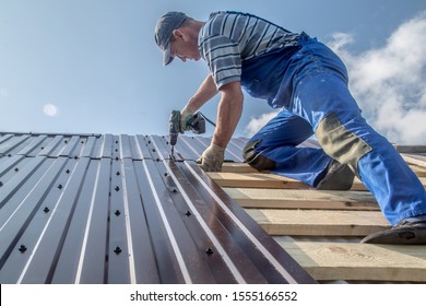 male builder performs work on the roof, fastens corrugated sheets