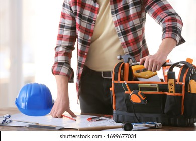 Male builder with tools in bag and house plan in office - Shutterstock ID 1699677031