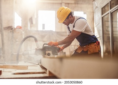 Male builder using wood cutting circular saw machine in workshop - Powered by Shutterstock