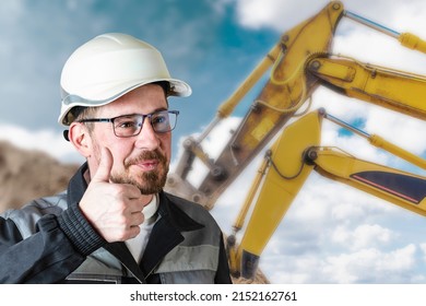 A Male Builder In A White Hard Hat Against A Blurred Background Of A Construction Site With A Blue Sky. Positive Civil Engineer With A Beard