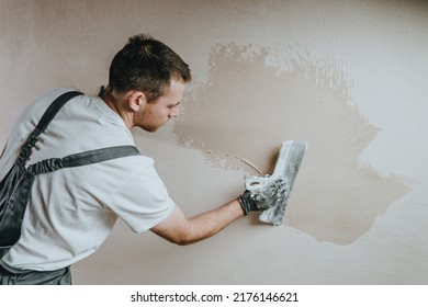 Male builder in work overalls plastering a wall using a construction trowel. Horizontal panorama banner with blank space for text. - Shutterstock ID 2176146621