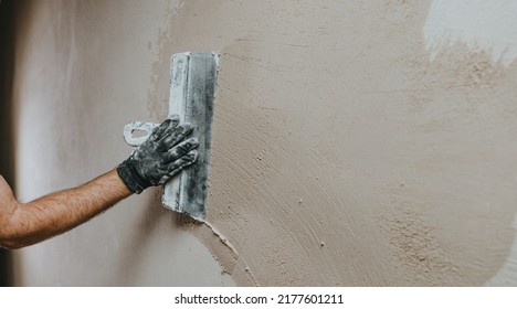 Male builder in work overalls plastering a wall using a construction trowel. Horizontal panorama banner with blank space for text. - Shutterstock ID 2177601211