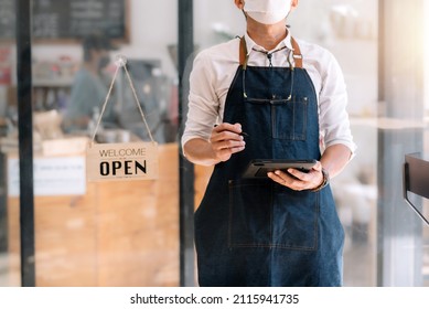 Male business owner standing holding a tablet with open sign board. - Shutterstock ID 2115941735