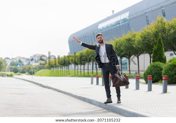 Male businessman can not catch free taxi at busy\
time. business man does not successfully stop a taxi on a city\
street. can\'t catch a car on the road waving his hand. standing on\
the sidewalk outside