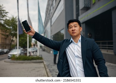 Male Businessman Catch Free Taxi At Busy Time. Asian Man Stop The Car On City Street. Guy Standing On The Road Waving His Hand Outside 