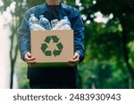 Male businessman holds a cardboard box with a water bottle and a recycling symbol. Recycling concept use of green technology Invest in green business Good green organization, clean community, etc.