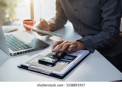 Male Businessman Working On Desk Office With Using A Calculator And Tablet To Calculate The Numbers, Finance Accounting Concept.