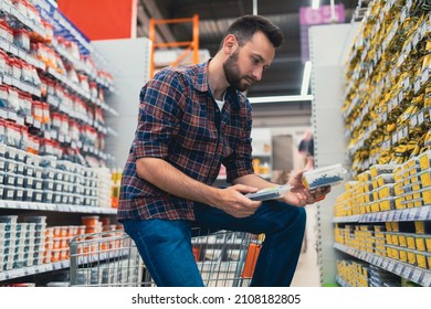 male buyer in a hardware store chooses screws and self-tapping screws