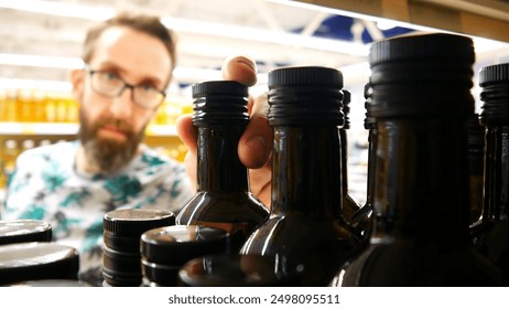 A male buyer taking a bottle of olive oil in a supermarket - Powered by Shutterstock