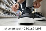 A male buyer tries on black leather boots in a shoe store close-up