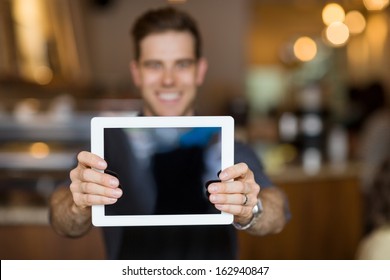 Male cafe owner showing digital tablet in cafeteria - Powered by Shutterstock