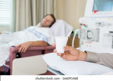 Male Cancer Patient's Hand Holding Glass Of Crushed Ice In Dialysis Room At Hospital