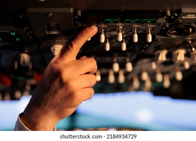 Male Captain Using Control Panel In Cockpit To Fly Airborne Aircraft, Pushing Power Engine Buttons And Switch On Dashboard Command. Using Lever And Handle With Windscreen. Close Up.