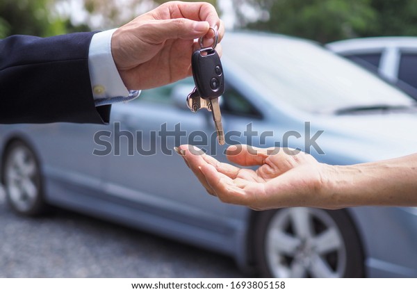 The male\
car dealer is delivering the keys to the woman bought or rented the\
car. sale and rental business\
concept