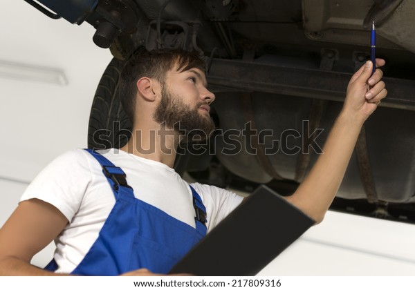 Male car\
mechanic working under car, Studio\
Shot
