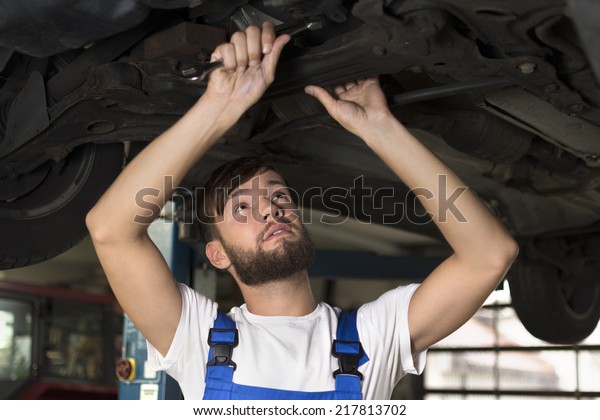 Male car\
mechanic working under car, Studio\
Shot
