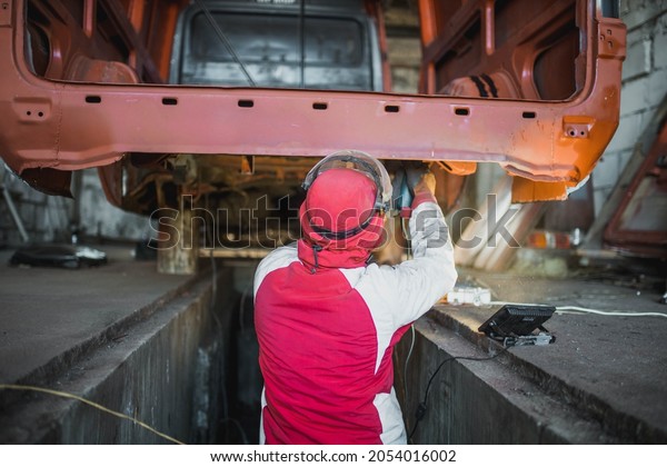 male car\
service worker cleans the bottom of the car body with a grinder.\
Waterproofing metal of a car\
body.