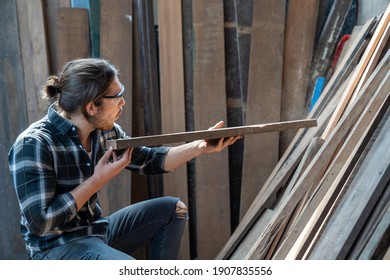 Male Carpenter Cleaning And Examining Piece Of Wood In Carpentry Workshop. Carpenter Working His Job At His Workstation