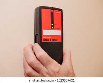 Male carpenter using electronic stud finder to locate interior wall stud.