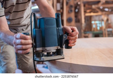 male carpenter working with hand-held power tools on a wooden table  - Shutterstock ID 2251876567