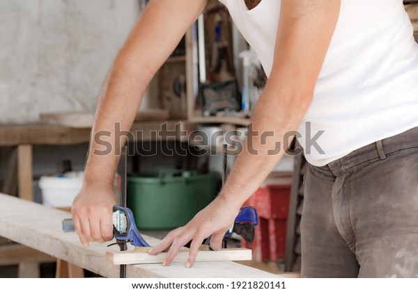 Male\
carpenter working with wood material in a\
garage.