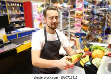 Male Cashier Checking Out Goods In Supermarket