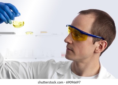 Male Caucasian Biotechnician In The Lab Examining Yellow Liquid In A Conical Flask