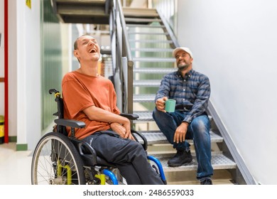 Male caucasian freelance and disabled coworker laughing and talking during coffee break at coworking - Powered by Shutterstock