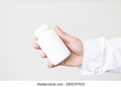 Male Caucasian Hand In A Lab Coat And A Holding A White Pill Bottle 