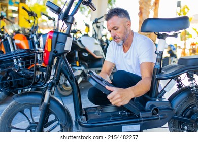 male charging battery process of electric scooter in rental store or parking - Shutterstock ID 2154482257