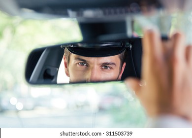 Male Chauffeur Sitting In A Car And Looking At His Reflection In A Mirror