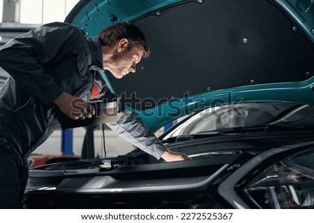Male checking technical condition of car engine