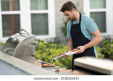 a male chef in an apron grills salmon steak with vegetables for dinner. A chef grilling fish on an open flame, preparing it with herbs and lemon. man cooking salmon on grill outdoor grill salmon fish - Powered by Shutterstock