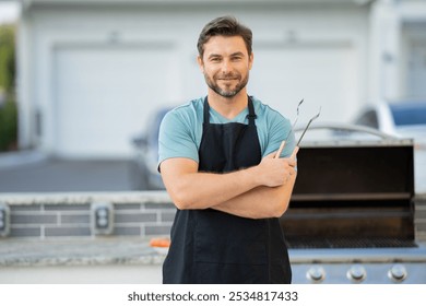 male chef in an apron stands by the grill outside and looks at camera. man is cooking on a grill. chef man at barbecue and grill . chef at barbecue and grill. Man grilling food on barbecue in backyard - Powered by Shutterstock