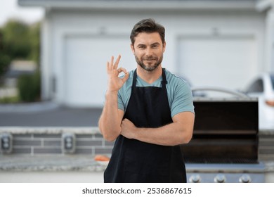 male chef in an apron stands by the grill outside and looks at camera. man is cooking on a grill. chef man at barbecue and grill . chef at barbecue and grill. Man grilling food on barbecue in backyard - Powered by Shutterstock