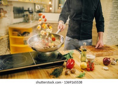 Male Chef Cooking Meat With Vetables Into The Pan