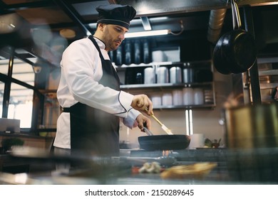 Male chef cooking while working at restaurant kitchen. - Powered by Shutterstock