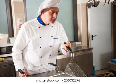 Male Chef Dressed In White Uniform Using A Deep Fryer