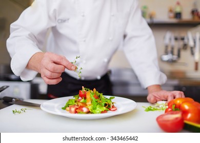 Male chef garnishing dish at the kitchen - Powered by Shutterstock