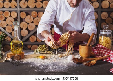 Male Chef Making Homemade Pasta With Flour And Eggs Over Old Wooden Table