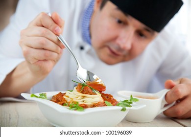 Male chef in restaurant kitchen is garnishing and preparing pasta dish - Powered by Shutterstock