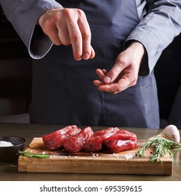 Male chef seasoning filet mignon steaks. Fresh meat, pepper salt, garlic and rosemary on wooden board. Modern restaurant cuisine backgroung - Shutterstock ID 695359615