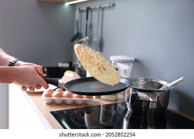 Male Chef Tossing Pancake In Frying Pan In Kitchen Closeup