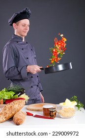  Male Chef Tossing Vegetables From Wok In Kitchen 