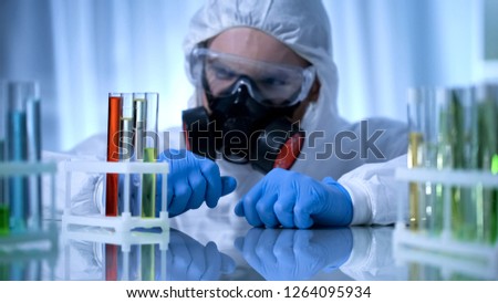 Male chemist checking test tubes with biohazard substance, toxicology testing