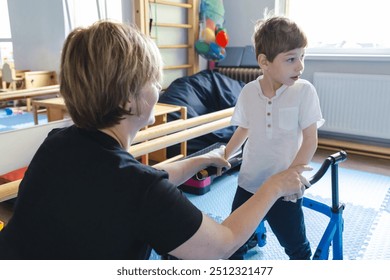 Male child with cerebral palsy actively participates in physical therapy with his therapist in a rehabilitation center during a training session with walker - Powered by Shutterstock