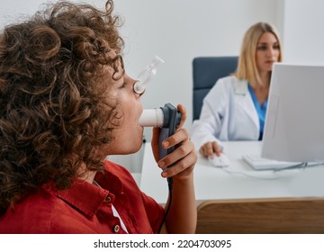 Male Child During Breathing Spirometry And Pulmonary Function Test Using Medical Spirometer With Doctor Looking At Test Results On Monitor