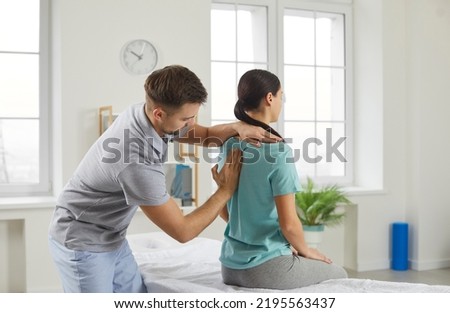 Male chiropractor, physiotherapist or osteopathy specialist examining a female patient with scoliosis or back ache. Physiotherapy, modern orthopaedic therapy, scoliosis treatment concept